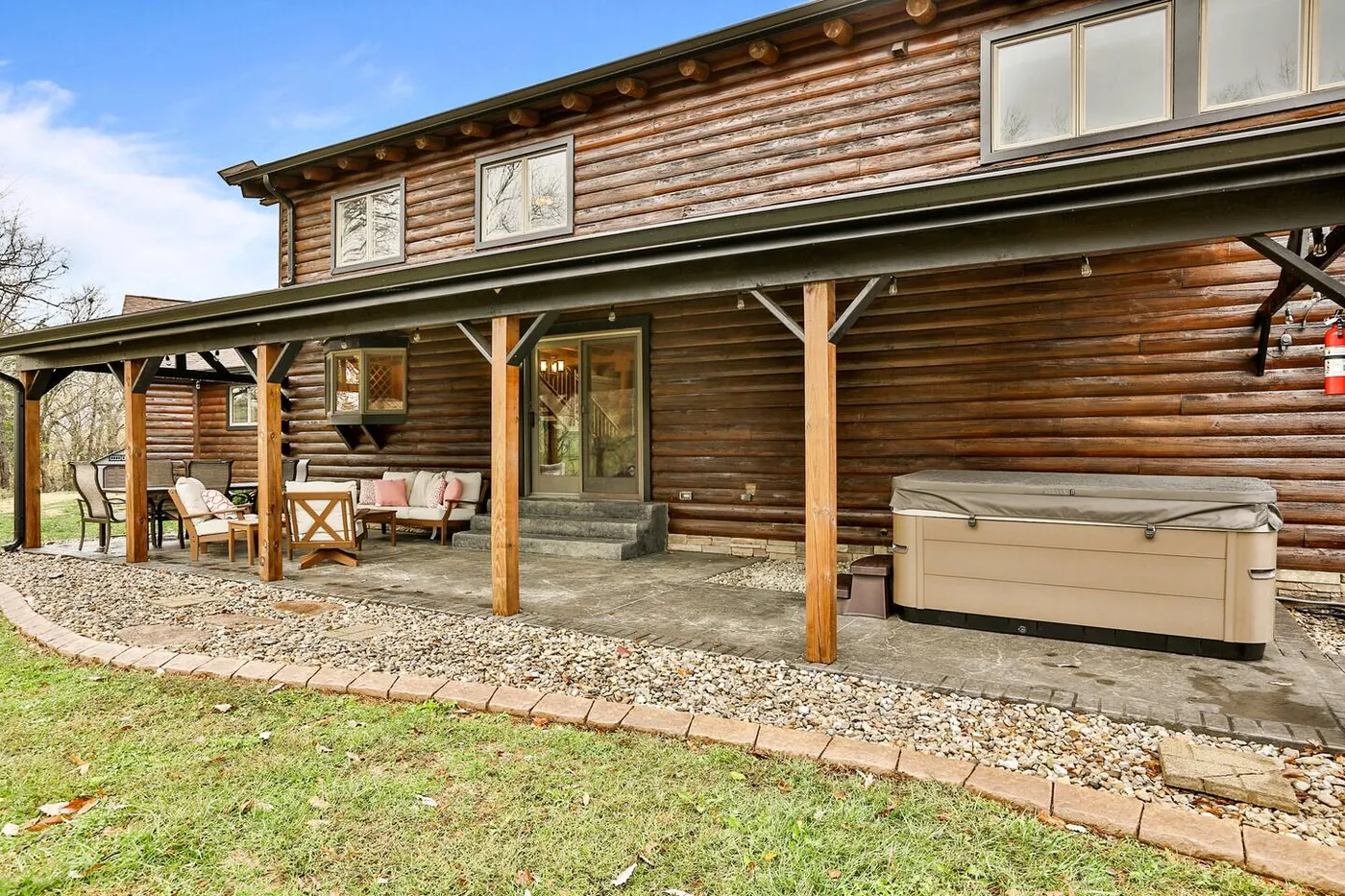 Covered patio with a hot tub overlooking the meadow